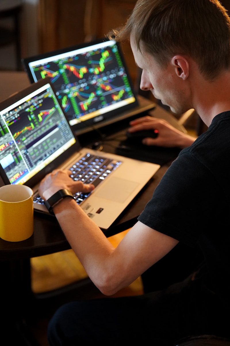 homme assis devant l'ordinateur portable et gère sa plateforme de trading